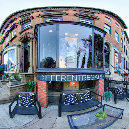 Building exterior with 'Different Regard' sign, surrounded by trees and parked cars.