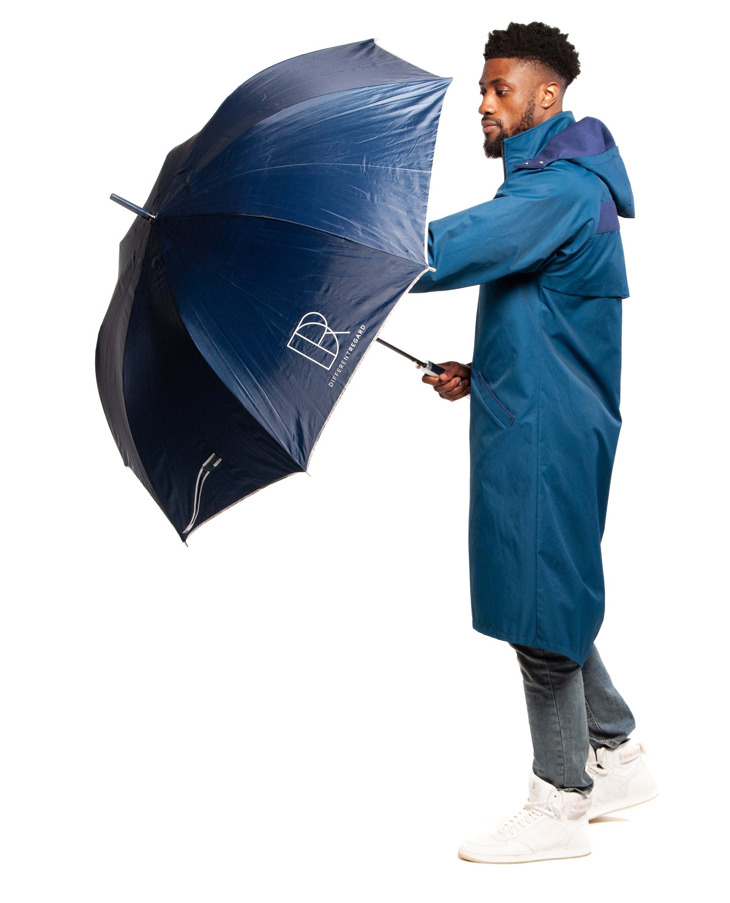 A person wearing a blue parka with a black zipper and turquoise reversible nylon fabric details, featuring a V cut bottom tail.